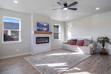 Living room with recessed lighting, light wood-style floors, a glass covered fireplace, and a ceiling fan