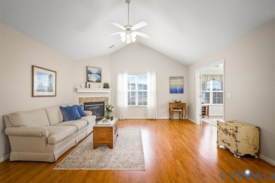 Living room featuring vaulted ceiling, a fireplace, light wood finished floors, and ceiling fan