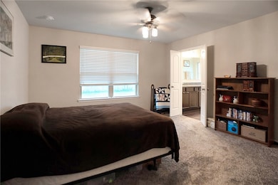 Bedroom with ceiling fan, carpet flooring, and ens