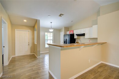 Kitchen with black fridge, exhaust hood, a peninsu