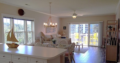 Dining room with crown molding, healthy amount of natural light, dark wood finished floors, a ceiling fan, and a chandelier