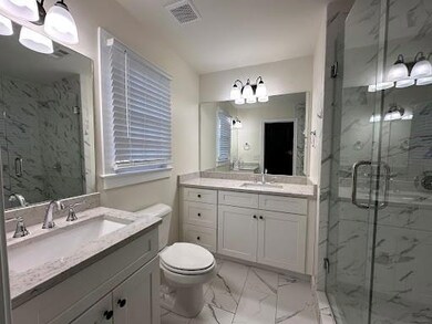 Full bathroom featuring marble finish floors, a marble finish shower, two vanities, and a chandelier