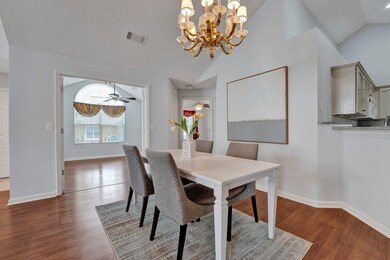 Dining room with ceiling fan with notable chandelier, dark hardwood / wood-style floors, and lofted ceiling