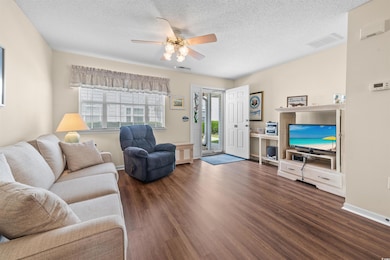 Living area featuring a ceiling fan, dark wood-style floors, a textured ceiling, and baseboards