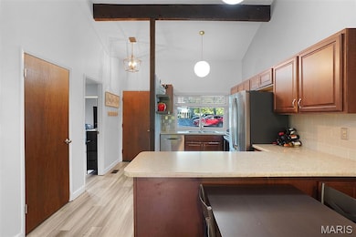 Kitchen with a peninsula, backsplash, light countertops, beamed ceiling, and high vaulted ceiling