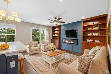 Staging option furniture split. Living area with a fireplace, a chandelier, wood finished floors, a ceiling fan, and recessed lighting. Virtually staged.