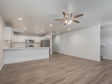 Kitchen featuring light hardwood / wood-style flooring, white cabinets, stainless steel appliances, and ceiling fan