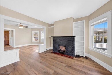 Virtually Staged Unfurnished living room with visible vents, a brick fireplace, baseboards, ceiling fan, and light wood-style flooring