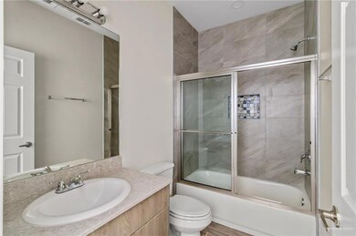 Full bathroom featuring combined bath / shower with glass door, vanity with extensive cabinet space, and toilet