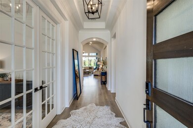 Hall featuring an inviting chandelier, wood-type flooring, crown molding, and french doors