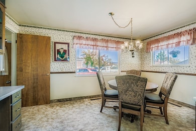 Dining area featuring wallpapered walls, healthy amount of natural light, a chandelier, and light colored carpet