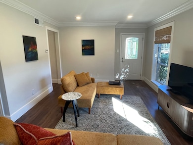 Living area with crown molding, dark wood-type flooring, and recessed lighting