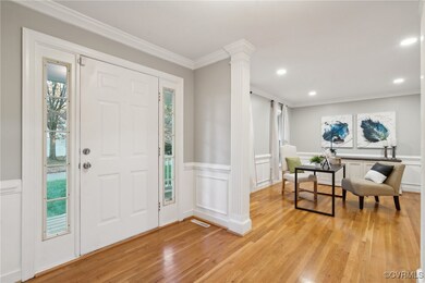 Foyer entrance with decorative columns, crown molding, a healthy amount of sunlight, and light hardwood / wood-style floors