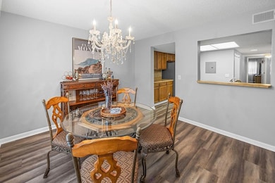 Dining space with a chandelier, dark wood-style floors, and baseboards
