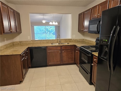 Kitchen with black appliances, a sink, light tile