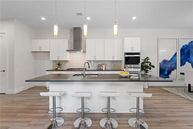 Kitchen with light wood finished floors, dark cou