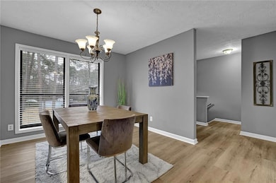 Dining space featuring a chandelier, light wood-style flooring, and a textured ceiling