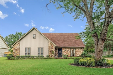View of front of home with stone siding and a front lawn