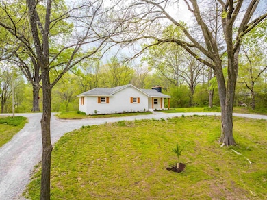 View of front of house with a front lawn, driveway, and a chimney