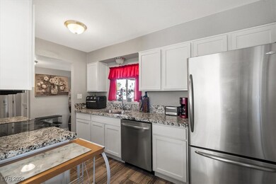 Kitchen with stainless steel appliances, light stone countertops, and white cabinetry
