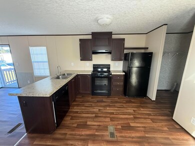 Kitchen with dark brown cabinets, black appliances, light countertops, dark wood finished floors, and a textured ceiling
