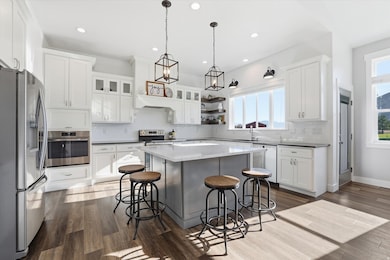 Kitchen featuring stainless steel appliances, subway tile backsplash, white cabinets, dark stone countertops, and a center island with granite