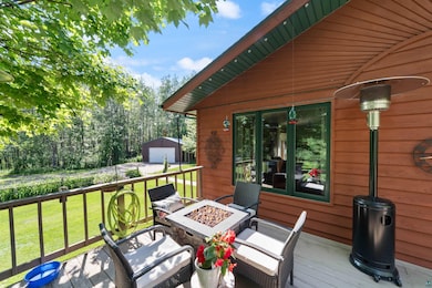 Wooden terrace with a fire pit, an outbuilding, and a yard