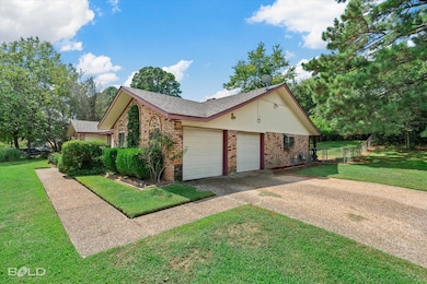 View of side of property featuring brick siding, a shingled roof, driveway, and a garage