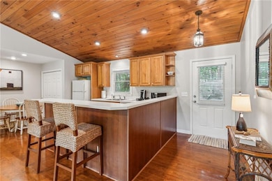 Kitchen with freestanding refrigerator, vaulted ceiling, dark wood-style flooring, a sink, and wood ceiling
