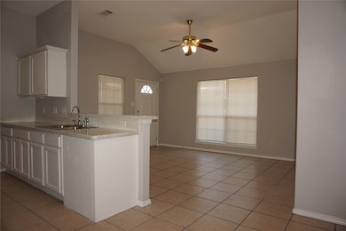 Kitchen featuring white cabinetry, lofted ceiling, a peninsula, open floor plan, and light tile patterned floors