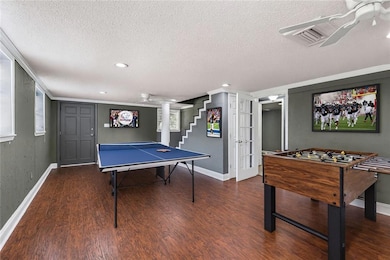 Recreation room with dark wood-style flooring, a textured ceiling, recessed lighting, and ornamental molding