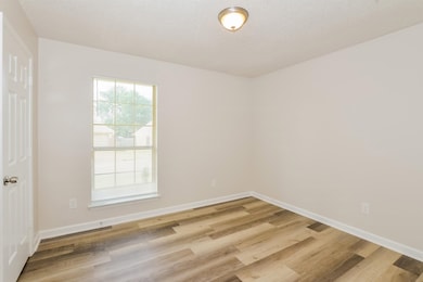 Spare room featuring light wood-type flooring and baseboards