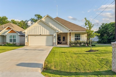 View of front of home featuring board and batten siding, a garage, a front yard, and concrete driveway