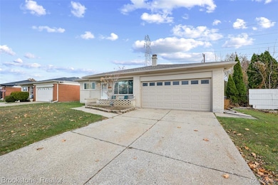 Single story home featuring brick siding, driveway, a garage, a front lawn, and a chimney