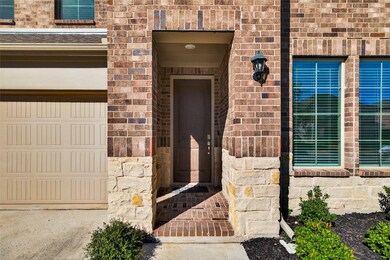 View of exterior entry featuring a garage and brick siding