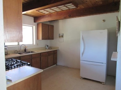 Kitchen with wood ceiling, beam ceiling, white fridge, and light tile patterned floors
