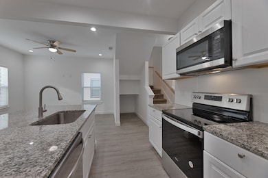 Kitchen featuring ceiling fan, appliances with stainless steel finishes, white cabinetry, and recessed lighting
