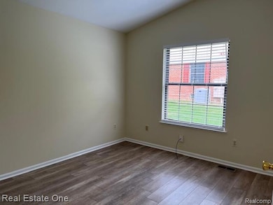 Unfurnished room with wood finished floors and lofted ceiling