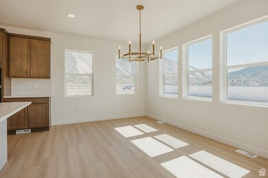 Unfurnished dining area with light wood-style flooring, recessed lighting, a mountain view, and a chandelier