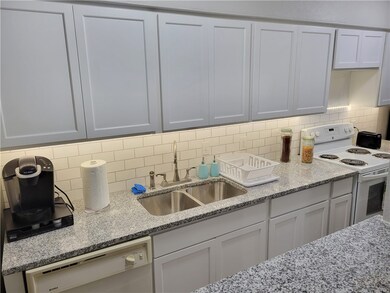 Kitchen featuring white appliances, a sink, backsp