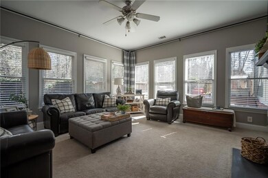 Carpeted living room with a ceiling fan, visible v