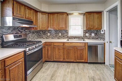 Kitchen with light wood-type flooring, appliances with stainless steel finishes, tasteful backsplash, and sink