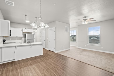 Kitchen featuring hanging light fixtures, white cabinets, open floor plan, a kitchen breakfast bar, and a peninsula