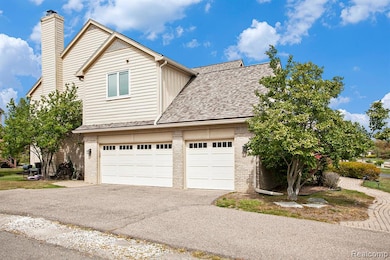 View of front facade featuring brick siding, a shingled roof, a garage, driveway, and a chimney