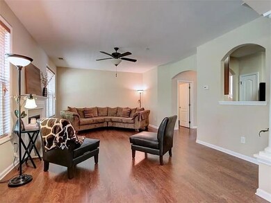 Living room featuring arched walkways, a ceiling fan, wood finished floors, and healthy amount of natural light
