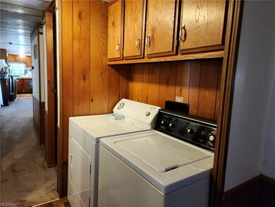 Clothes washing area featuring wood walls, washing machine and dryer, and dark carpet