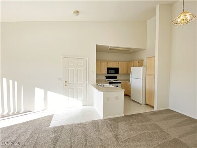 Kitchen featuring white appliances, light brown cabinets, light countertops, open floor plan, and light colored carpet