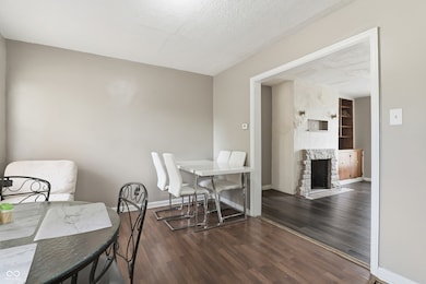 dining space with dark wood-style floors, a textured ceiling, and a fireplace with flush hearth