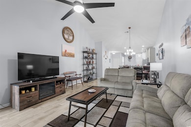 Living area with a chandelier, light wood-type flooring, and ceiling fan