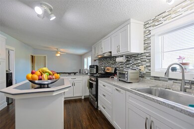 Kitchen with white cabinets, stainless steel gas stove, tasteful backsplash, light countertops, and a textured ceiling